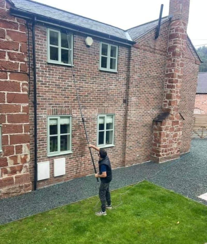 Hot water-fed pole cleaning an upstairs window in Telford, streak-free glass